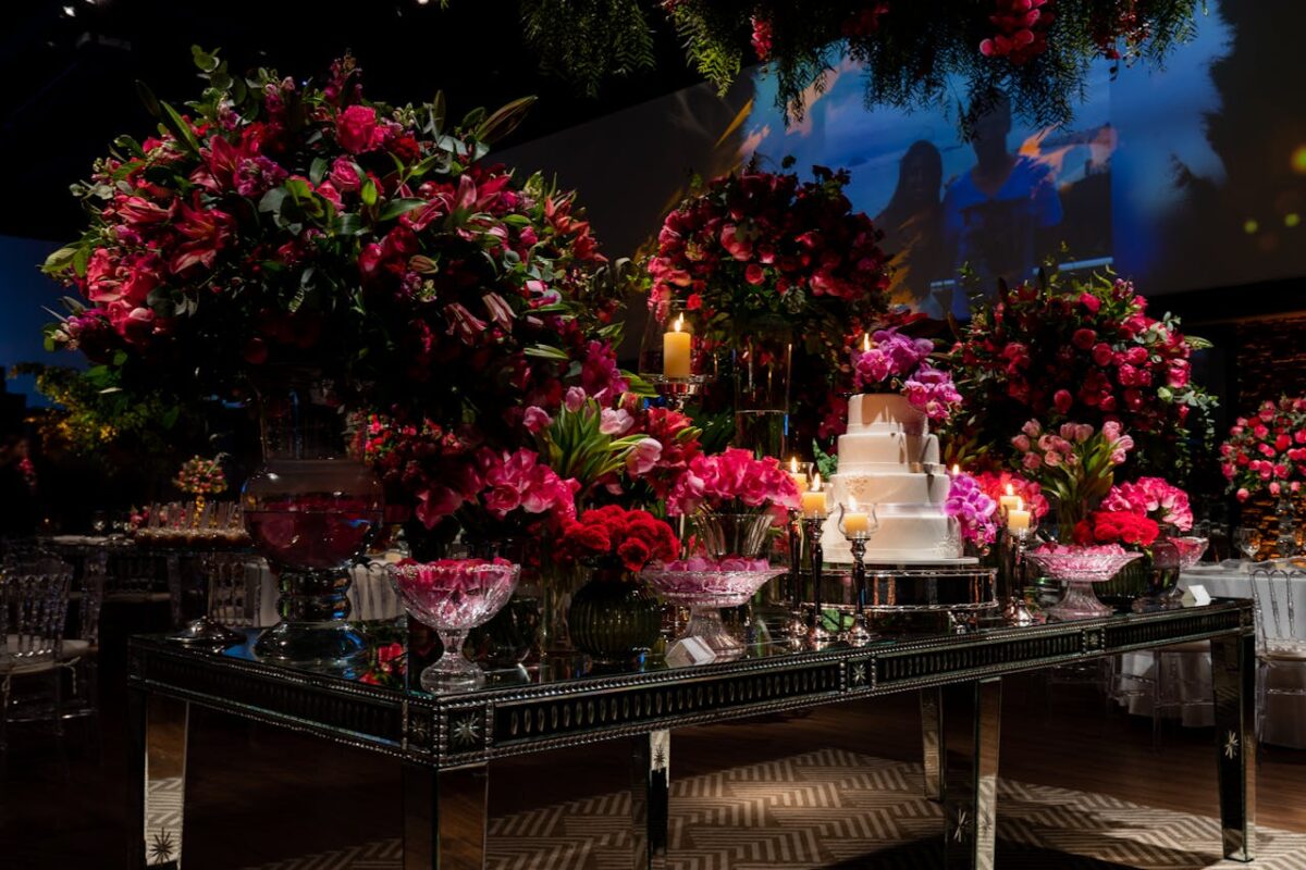 Lavish wedding reception table adorned with vibrant floral arrangements and a tiered cake.